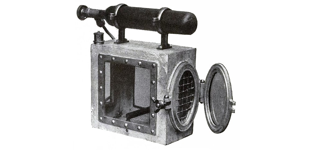 Canary revival cage with an oxygen cylinder as the handle. Other parts include escape valves at the top and back to release excess pressure. This cage was designed by Siebe Gorman & Company (01914).