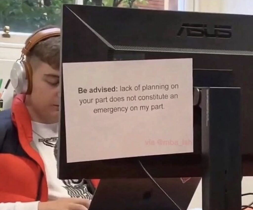Someone working at a computer with a note on the back saying: Be advised, Lack of planning on your part does not constitute and emergency on my part